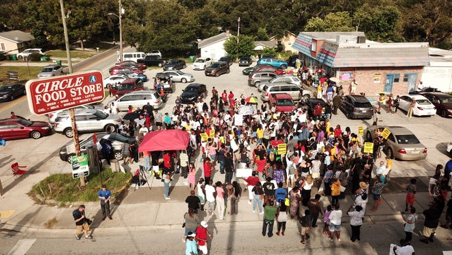 In this Sunday, July 22, 2018 photo, family, friends and demonstrators gather in a parking lot in Clearwater, Fla., where Markeis McGlockton, 28, was shot and killed in an altercation. The family of McGlockton issued an appeal through their attorney for the public to put pressure on State Attorney Bernie McCabe to file charges against Michael Drejka, who fatally shot the father of three last Thursday during an argument over a handicapped parking space outside a convenience store. (Luis Santana/Tampa Bay Times via AP)
