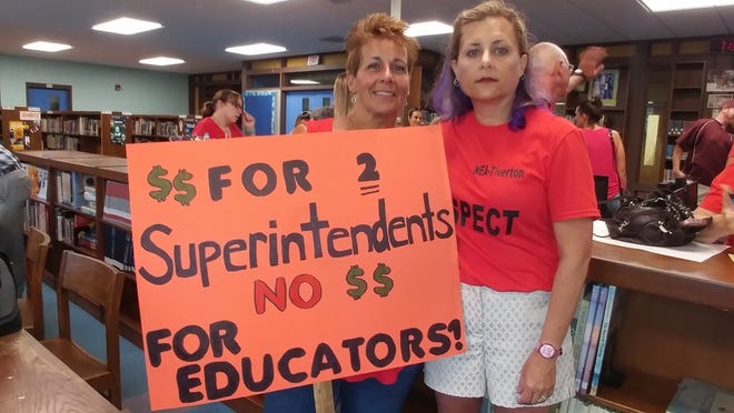Lynn Nicholas, left, a Tiverton high school guidance counselor, and Amy Mullen, president of NEA Tiverton and special education teacher, hold one of several signs teachers brought to Tuesday's School Committee meeting to show their frustration with teacher contract negotiations. [Marcia Pobzeznik ]