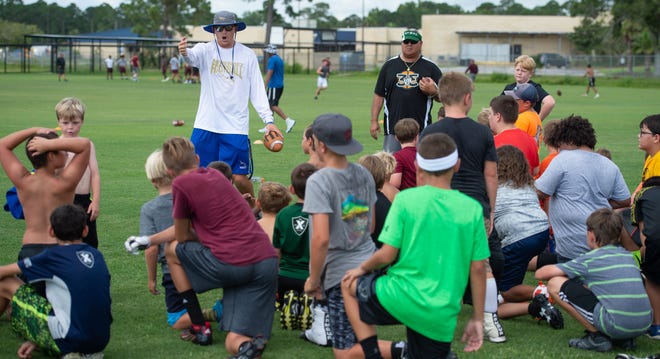 Pedro Menendez High School head football coach Kyle Skipper talks to a group of Police Athletic League football players at a camp at St. Augustine High School on July 18. Standing with Skipper is St. Johns County Sheriff resource deputy Rafael Fuenas [PETER WILLOTT/THE RECORD]