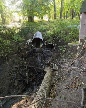 Erie property developer Rick Griffith sued Millcreek Township over extensive damage to his house and property following extensive erosion to the property that he says was caused by improperly managed storm water runoff from this pipe behind the house and the shed at right. [FILE PHOTO/ERIE TIMES-NEWS]