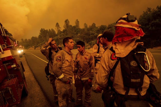 Firefighters discuss plans while battling the Carr Fire in Shasta, Calif., on Thursday, July 26, 2018. (AP Photo/Noah Berger)