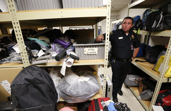 Lt. Scott Bekemeier, a police officer with thef Columbus Regional Airport Authority, shows some of the items ready for pickup by an auction house because the lost items couldn't be placed with owners. The airport keeps items for 90 days before sending them to auction. [Adam Cairns / Dispatch]