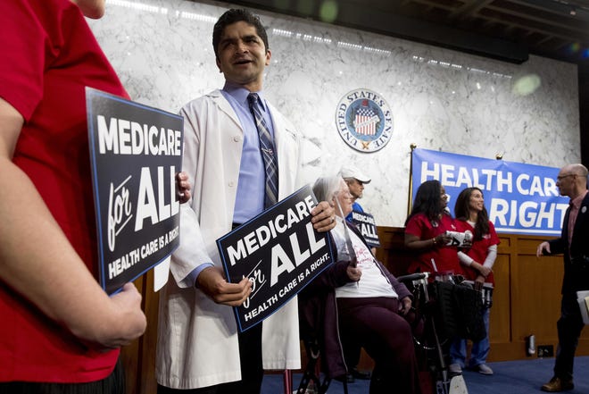 A doctor and other supporters gather before senators arrive for a news conference on Capitol Hill in 2017 to unveil Medicare for All legislation. [AP Photo/Andrew Harnik, File]