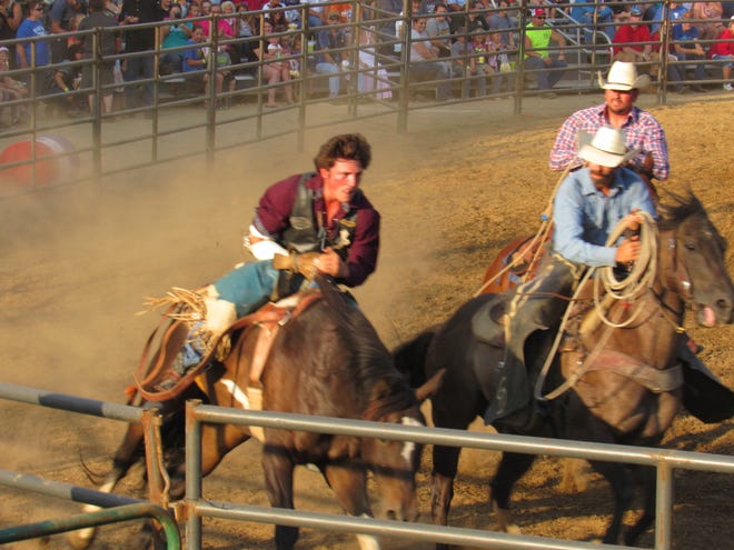 A bronco rider races to get off the bucking horse to avoid being injured or thrown off. Assistants race beside the rider to assist in the escape. July 28 also happened to be the National Day of the Cowboy.