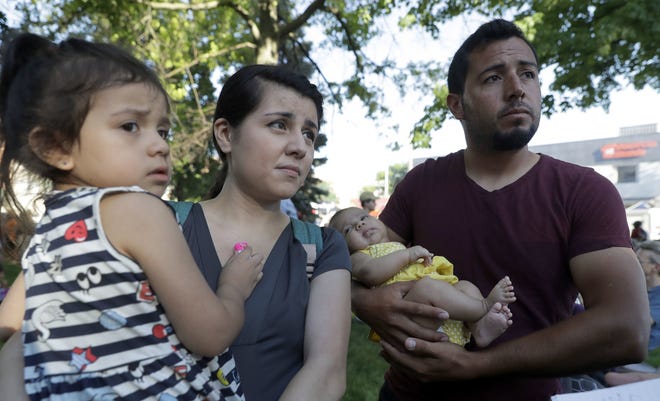 Pepe Urzua, a roofer who arrived from Mexico eight years ago, cradles his two-month-old daughter, Luna, as his wife, Betty, holds their daughter, Scarlet, during the First Fridays street festival in Goshen, Ind., on June 1, 2018. "It's a place where you want to raise your kids." Urzua said. But his wife, who came to the U.S. when she was two, said opposition to the proposed ICE facility does not mean immigrants are accepted. "I've seen a lot of people with Trump stickers on their trucks. They're a lot of people here who don't like us," she said. (AP Photo/Charles Rex Arbogast)