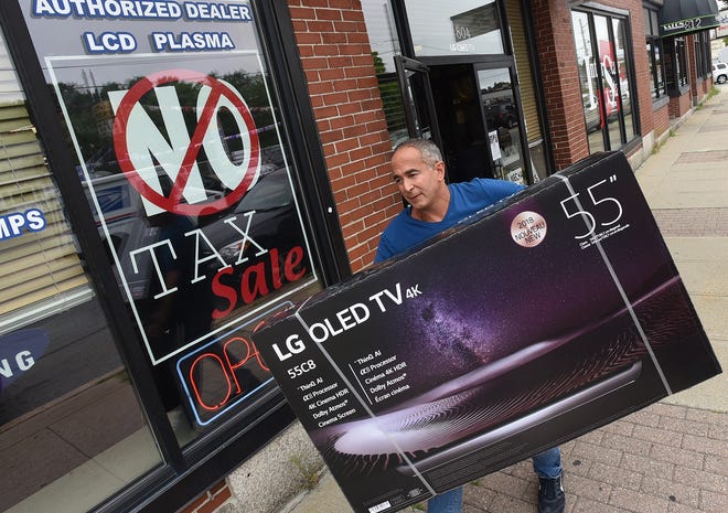George Saber carries a television from his store on Pleasant Street, saying he's thanksful that the big screen TVs are getting lighter as he gets older. [Herald News Photo | Jack Foley]