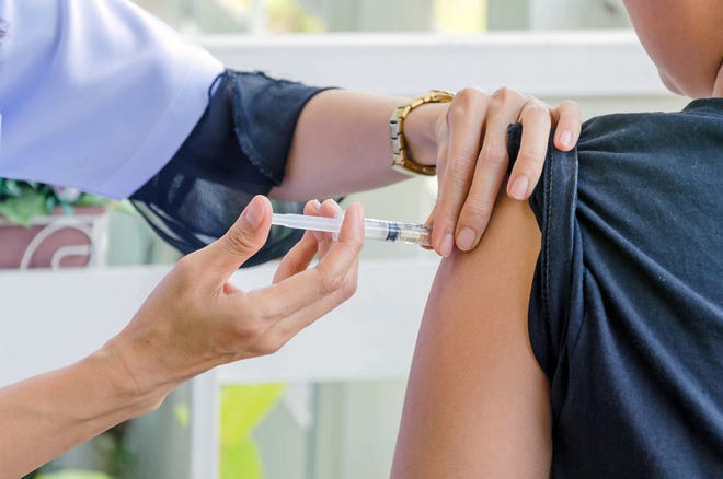 A doctor gives a student his shots before the start of school. [Shutterstock]