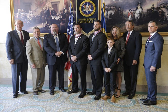 U.S. Marshal for the Southern District of Georgia David Lyons, left, Georgia First Congressional Rep. Buddy Carter, Supervisory Deputy Ramiro Suarez Jr., Deputy Marshals James Turner and Robert Doherty, Connor and Terry Carothers, the family of late Deputy Commander Patrick Carothers, S.C. First District Rep. Mark Sanford and U.S Attorney for the Southern District of Georgia Bobby Christine pose for a photo at the Tomochichi Federal Building and U.S. Courthouse on Wendesday. The four officers were awarded the Congressional Medal of Bravery for a 2016 warrant service in Long County. [Will Peebles/Savannah Morning News]