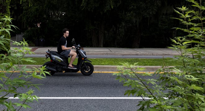 A man rides his scooter down Museum Road on the University of Florida campus on Friday. UF sold 6,268 scooter parking decals during the 2016-17 academic year. [Lauren Bacho/Staff photographer]