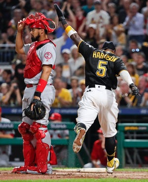 Pittsburgh Pirates' Josh Harrison (5) celebrates after scoring next to St. Louis Cardinals catcher Francisco Pena during the eighth inning of a baseball game Friday, Aug. 3, 2018, in Pittsburgh. The Pirates won 7-6. (AP Photo/Keith Srakocic)