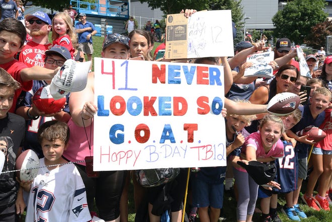 Fans hold up signs celebrating Tom Brady's birthday as he comes near to sign autographs at Gillette Stadium on Friday.