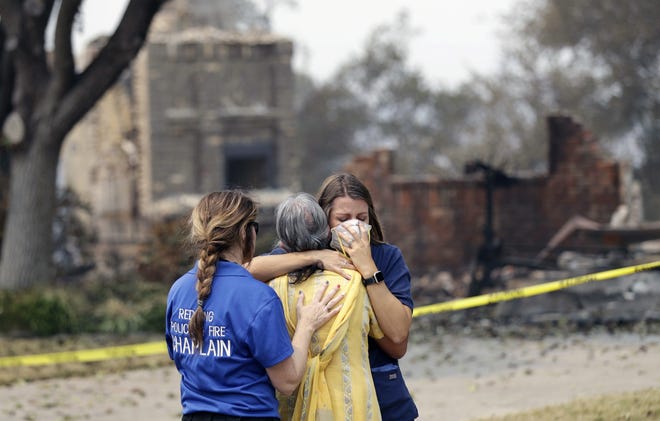 A resident, in yellow, wishing not to be identified, is comforted after seeing her fire-ravaged home for the first time in Redding, Calif. [MARCIO JOSE SANCHEZ]