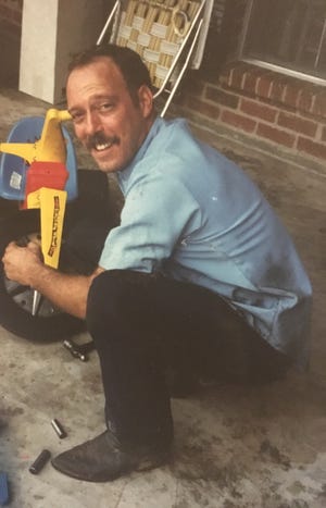 Brian 'Bumpy' Windsor repairing his son's Hot Wheel bike in this 1987 photograph. [Contributed photo]