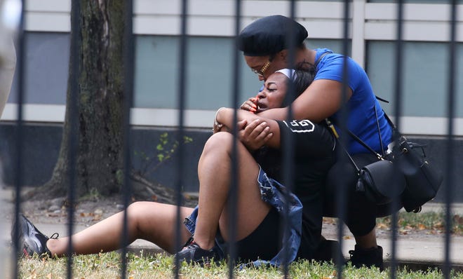 In this Sunday, Aug. 5, 2018 photo, two women cry outside the Stroger Hospital in Chicago after they were asked to leave due to overwhelming crowds of family and friends of shooting victims. Police Superintendent Eddie Johnson plans to discuss the weekend violence during a Monday news conference. (Antonio Perez/Chicago Tribune via AP)