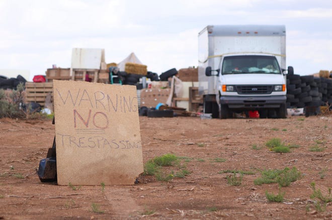 This Aug. 5, 2018 photo shows a "no trespassing" sign outside the location where people camped near Amalia, N.M. Three women believed to be the mothers of 11 children found hungry and living in a filthy makeshift compound in rural northern New Mexico have been arrested, following the weekend arrests of two men, authorities said Monday, Aug. 6. (Jesse Moya/Santa Fe New Mexican via AP)