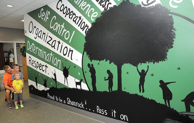 Barnesville Middle School Principal Casey Mayo, shows his sons, Parker, left and Casin, the new large mural in the office area of the school. It was painted by local artist Twila Fisher. Students and staff returning this year will be able to see the positive words it provides.