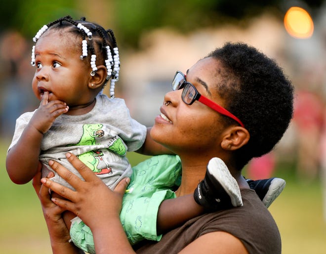 RON JOHNSON/JOURNAL STAR Resident Cheyenne Lowe holds her 11-month old son Tyron Jr., during the Center Bluff Neighborhood Association's gathering at Columbia Park for the National Night Out Against Crime event on Tuesday.