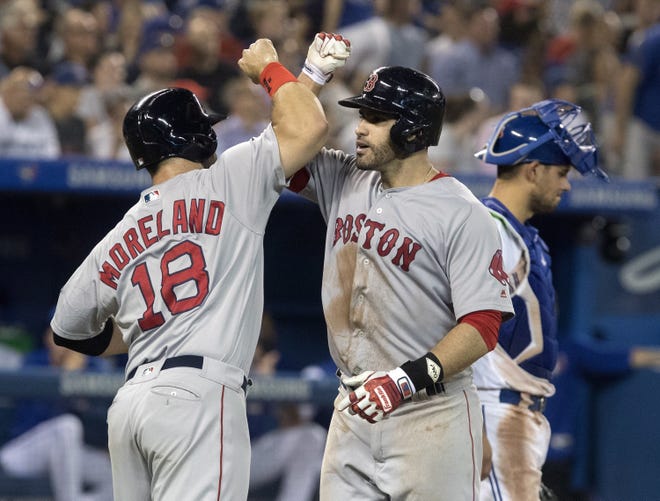 Red Sox designated hitter J.D. Martinez is greeted at home plate by Mitch Moreland after hitting a three-run home run during the eighth inning of Boston's 10-7 win in 10 innings over the Blue Jays in Toronto on Tuesday night.