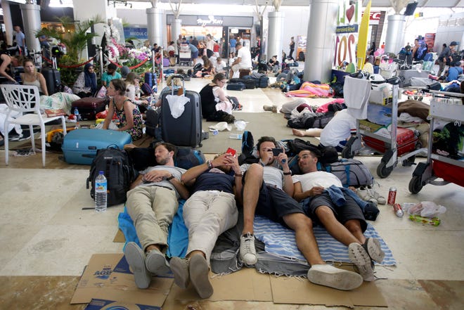 Foreign tourists rest on the floor while waiting for their flights at Lombok International Airport, following an earthquake in Praya, Lombok Island, Indonesia, Tuesday, Aug. 7, 2018. Thousands left homeless by the powerful quake that ruptured roads and flattened buildings on the Indonesian tourist island of Lombok sheltered Monday night in makeshift tents as authorities said rescuers hadn't yet reached all devastated areas. (AP Photo/Firdia Lisnawati)