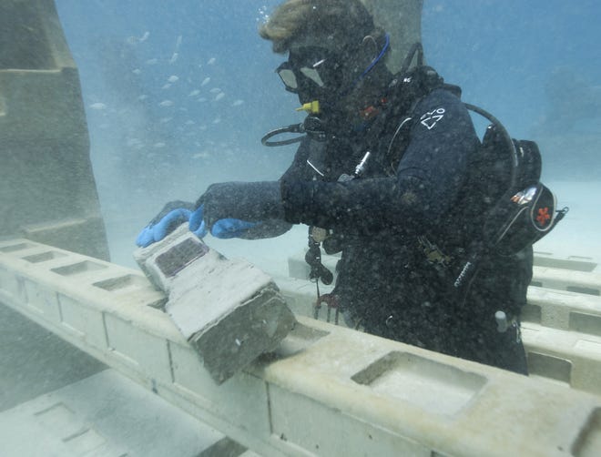 In this July 19, 2018 photo, Jim Hutslar, operations¬†director for Neptune Memorial Reef, prepares to install a memorial plaque for Buel and Linda Payne, affixed to a cement baluster mixed with their ashes, at the Neptune Memorial Reef near Miami Beach, Fla. The cemetery is already home to the cremated remains of about 1,500 people and is welcoming thousands more seeking life in the afterlife. (AP Photo/Wilfredo Lee)