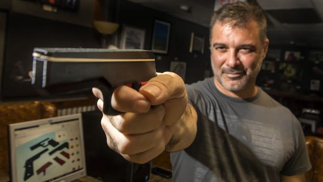 Alex Lorenzo, a 3D designer who operates Da Vinci's 3D Lounge in Lake Park, fires his 3-D printed rubber band gun Monday, August 6, 2018. (Lannis Waters / The Palm Beach Post)