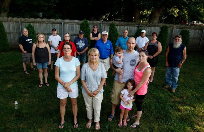 Residents of the Coventry neighborhood that abuts Ferrara Mechanical Services gather on Helen Avenue, where noise, fumes and the sight of trucks parked along their fence line have made their lives miserable. In the foreground, from left, are Diane Salvas, Cathy Theroux, and Tyler and Allison Albert, with their children, Regan, nine months, and Katherine, 3. [The Providence Journal / Kris Craig]