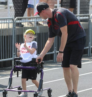 Kaelyn Napier,6 of New Philadelphia is excited to finish the 50 yard walk with her Dad Alex during the Outstanding Athletes Track and Field Community event Sunday at Woody Hayes Quaker Stadium. (TimesReporter.com / Jim Cummings)