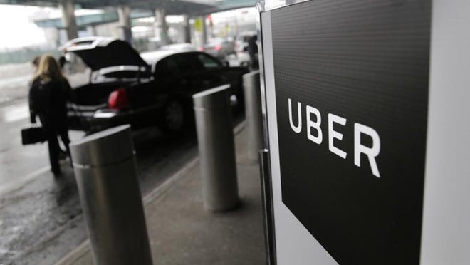 In this March 15, 2017 file photo, a sign marks a pick-up point for the Uber car service at LaGuardia Airport in New York.