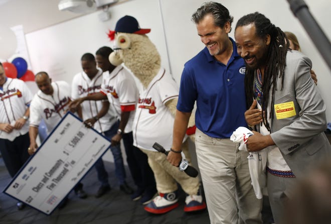 FOX Sports South broadcaster Chip Caray, left, presents Lemuel "Life" LaRoche, founder Athens-based youth development organization Chess and Community, with a check for $5,000 on Wednesday to benefit the group. [Photo/Joshua L. Jones, Athens Banner-Herald]
