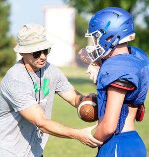 Pretty Prairie head coach Steve Puetz demonstrates how to properly hand off the ball with Lucas Detter during football practice, Wednesday, Aug. 15, 2018. [Jesse Brothers/HutchNews]
