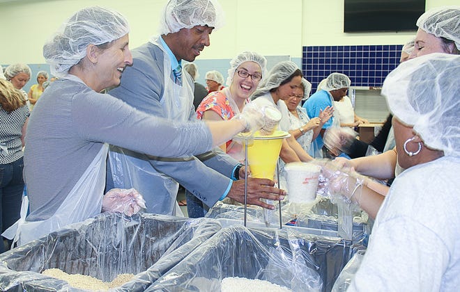 Otis A. Mason Elementary School principal Nigel Pillay, center, works with staff members of his school to package 10,000 meals in the school cafeteria to be distributed to need people in St. Johns County earlier this month. [BRIT McNEELY/CONTRIBUTED]