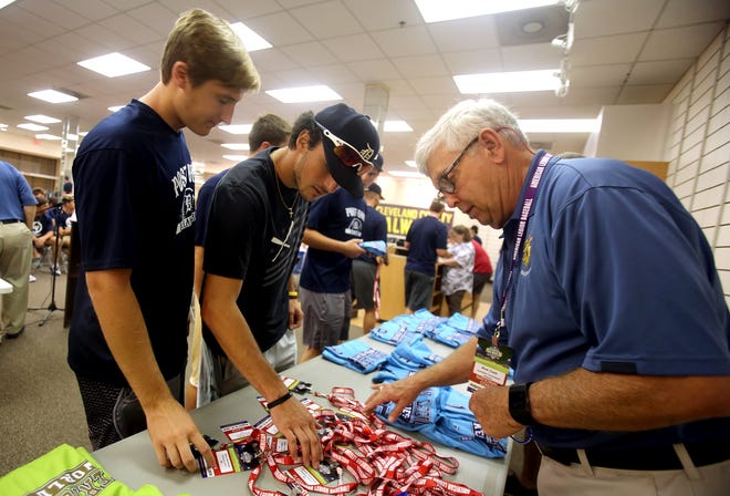 Rick Cash helps Chris Ludman and Jonathan Golebiowski of Delaware Post 1 with picking up their jerseys at orientation on Tuesday. [Brittany Randolph/The Star]