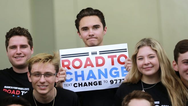 David Hogg (center) holds a “Road to Change” sign during a press conference at the Parkland Amphitheater Monday, June 4, 2018. A handful of teens, graduates and current students will be sacrificing their summer vacations to tour the nation for a voter drive. Using their new-found fame, a product of their outcry after surviving a deadly Feb. 14 school shooting, the students are embarking on a 20-state bus tour encouraging millions of voters to cast ballots in the midterm elections. The tour will be called “March for Our Lives: Road to Change” and will begin Friday, June 15 in Chicago, it was announced at the press conference. (Bruce R. Bennett / The Palm Beach Post)