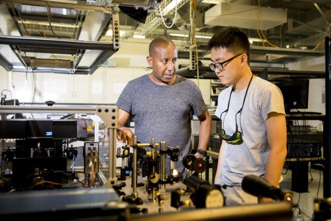 Yohannes Abate (L) works with PhD student Xingyang Li in the Nano Optics Lab. [Photo: Dorothy Kozlowski]