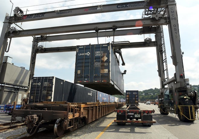 A shipping container is lifted from a container chassis and placed on a rail car by an overhead gantry crane at the CSX Intermodal Terminal in Worcester. [T&G Staff/Rick Cinclair]