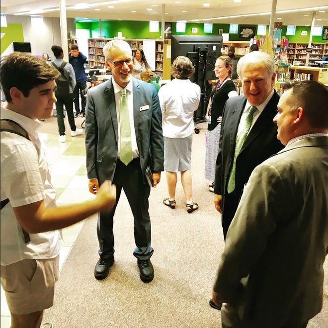 Former FPC Principal Dustin Sims, right, shows his successor, Robert Wallace, around the school. Here, they meet with a student and Superintendent James Tager, center, in the media center. [Courtesy of Flagler Schools]