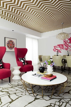 Gold brings a glamorous look to this space by Australian designer Greg Natale. He used a herringbone pattern on the ceiling, balanced by a modern abstract rug by Kelly Wearstler. The hot pink upholstery of Tom Dixon wingback chairs riffs from the Damien Hirst art on the wall behind, as well as other art in the room. This shot made the cover of the Australian magazine Design + Decoration.

Photo: Anson Smart