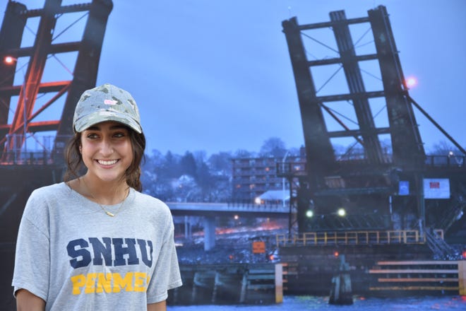 Jordan Woodford, who graduated this spring, is seen near her banner of the Brightman Street Bridge at sunset. [Courtesy photo]