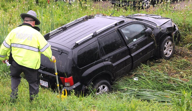 Trooper John Martin of the Cambridge post of the Ohio State Highway Patrol, surveys damage to this SUV after the driver lost control while traveling westbound on Interstate 70 Tuesday morning near the Route 209 on ramp. According to reports, the driver lost control on the wet roadway and slid off the road into a ditch heavily damaging the vehicle. The driver had minor injuries.
