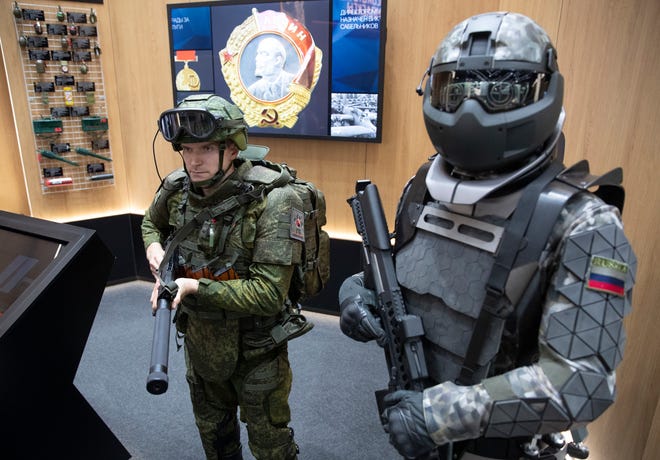 A man, left, wears a working sample of a passive exoskeleton combat gear, next to a mannequin dressed in a prototype of an active exoskeleton combat gear presented by the Russian Rostec company during the International Military Technical Forum Army-2018 in Alabino, outside Moscow, Tuesday, Aug. 21, 2018. Russia has displayed its latest weapons at a military show aimed at attracting more foreign customers. (AP Photo/Pavel Golovkin)