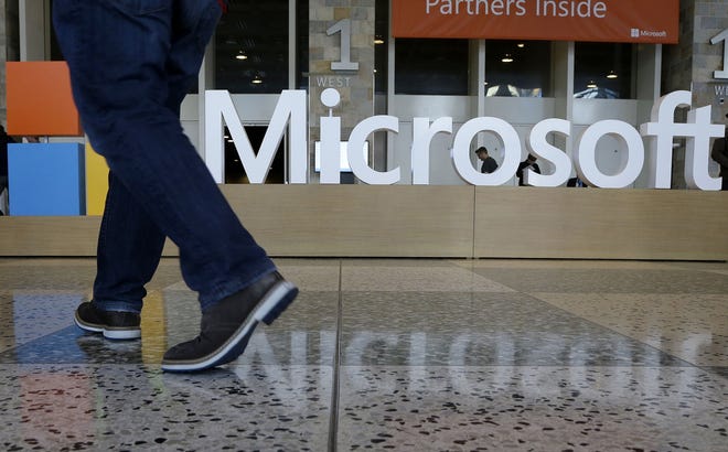 FILE - In this April 28, 2015, file photo, a man walks past a Microsoft sign set up for the Microsoft BUILD conference at Moscone Center in San Francisco. Microsoft has uncovered new hacking attempts by Russia targeting U.S. political groups ahead of the midterm elections. The company said Tuesday, Aug. 21, 2018, that a group tied to the Russian government created fake websites that appeared to spoof two American conservative organizations: the Hudson Institute and the International Republican Institute. Three other fake sites were designed to look as if they belonged to the U.S. Senate. (AP Photo/Jeff Chiu, File)