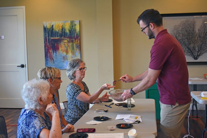 Wellness coordinator Keegan Hudson, instructor of the Kooking with Keegan class, gives resident Carrie Sawyer a sample of one of the recipes. [DeeAnna Wilkerson/Sun City Community Association]