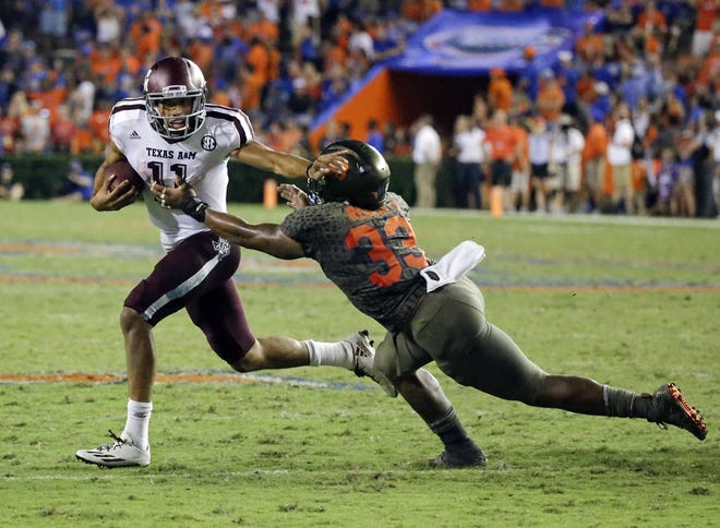 Texas A&M quarterback Kellen Mond (11) scrambles to get away from Florida linebacker David Reese (33) during the second half of a game on Oct. 14, 2017, in Gainesville. [AP Photo/John Raoux]