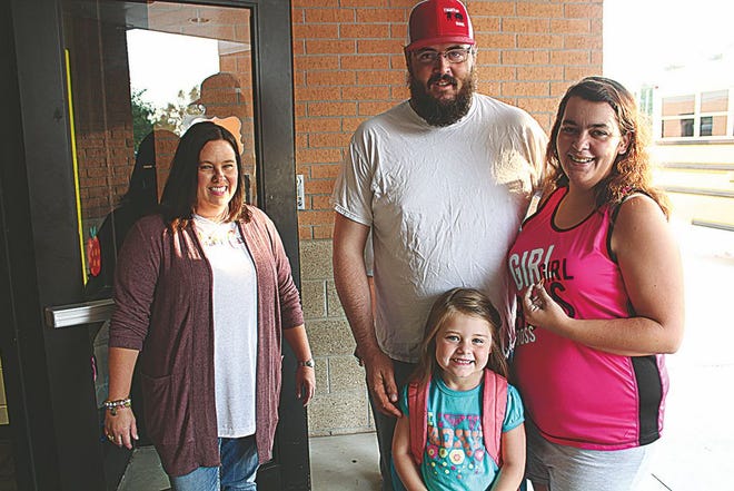 Zoe Reitan-Garrett, 6, arrives for her first day of school at Indian Camp Elementary last Thursday. She is shown here with her stepfather, Garrett Brown, and her mother, Ayron Brown. At left is Indian Camp Principal Amy Sanders, who welcomed them.