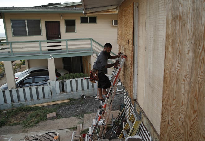 Kaipo Popa secures plywood to protect windows on a home in preparation for Hurricane Lane, Wednesday, Aug. 22, 2018, in Kapolei, Hawaii. As emergency shelters opened, rain began to pour and cellphone alerts went out, the approaching hurricane started to feel real for Hawaii residents.(AP Photo/John Locher)