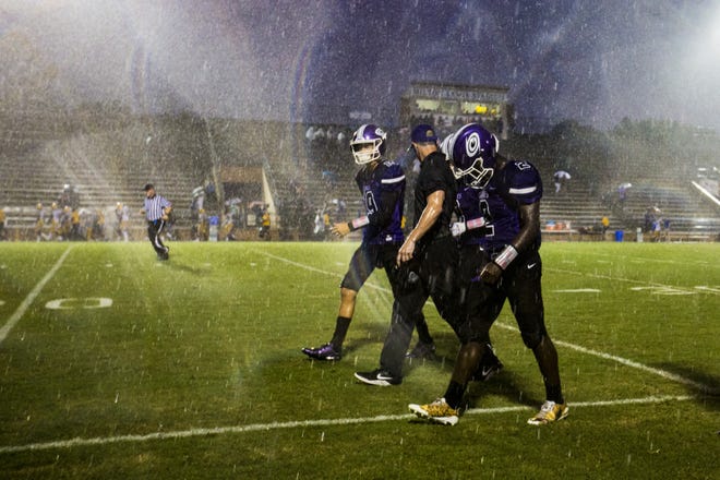 Gainesville High players and coaches exit the field during a lightning delay Thursday night at Citizens Field in a game against Columbia. [Lauren Bacho/Staff photographer]