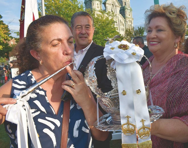 Fátima Ladino, of Dartmouth, kisses the scepter, one of the symbols of the Holy Ghost, while 2018 Great Feast Committee President João Medeiros and his wife Ana look on.