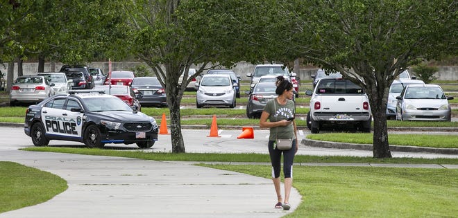 An Ocala police officer patrols the parking lot at West Port High School as a mother arrives to pick up her child on Wednesday afternoon during a Code Yellow. [Doug Engle/Ocala Star-Banner]