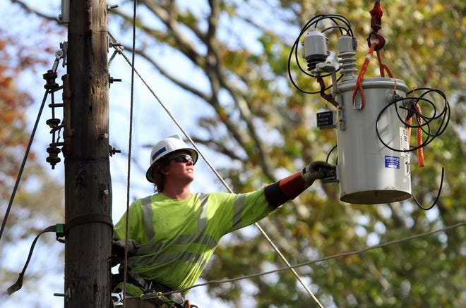 A National Grid worker repairs damage after a storm last fall. The Rhode Island Public Utilities Commission approved changes to electricity and gas distribution rates for the utility company on Friday. [The Providence Journal / Bob Breidenbach]
