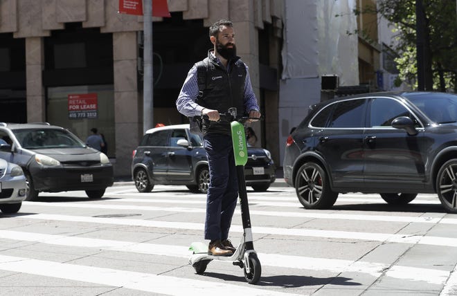 A man rides a motorized scooter as he approaches Market Street in San Francisco on April 17. [AP Photo/Jeff Chiu, File]
